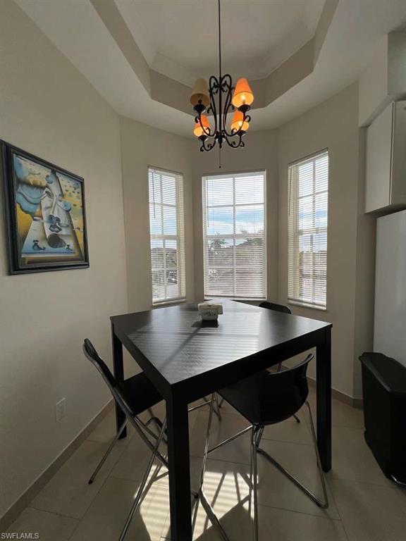 Bay window dining area featuring a tray ceiling and a wrought iron chandelier