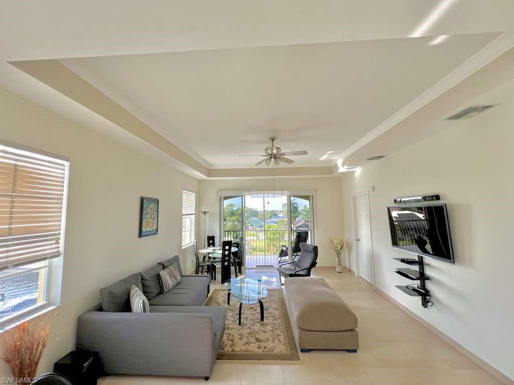 Open-concept living area with tray ceilings and crown molding