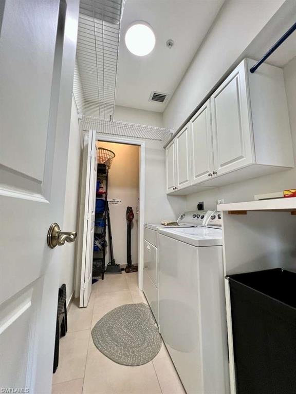 Dedicated utility space featuring a washer and dryer, complemented by white upper cabinetry