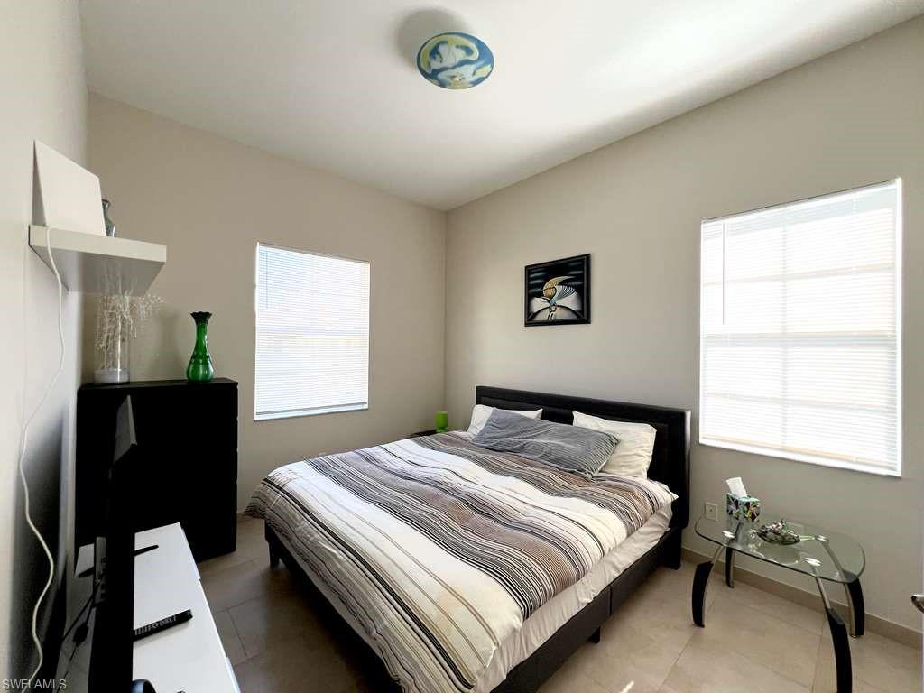 Room featuring two windows with horizontal blinds, light-toned wall paint, and tile flooring