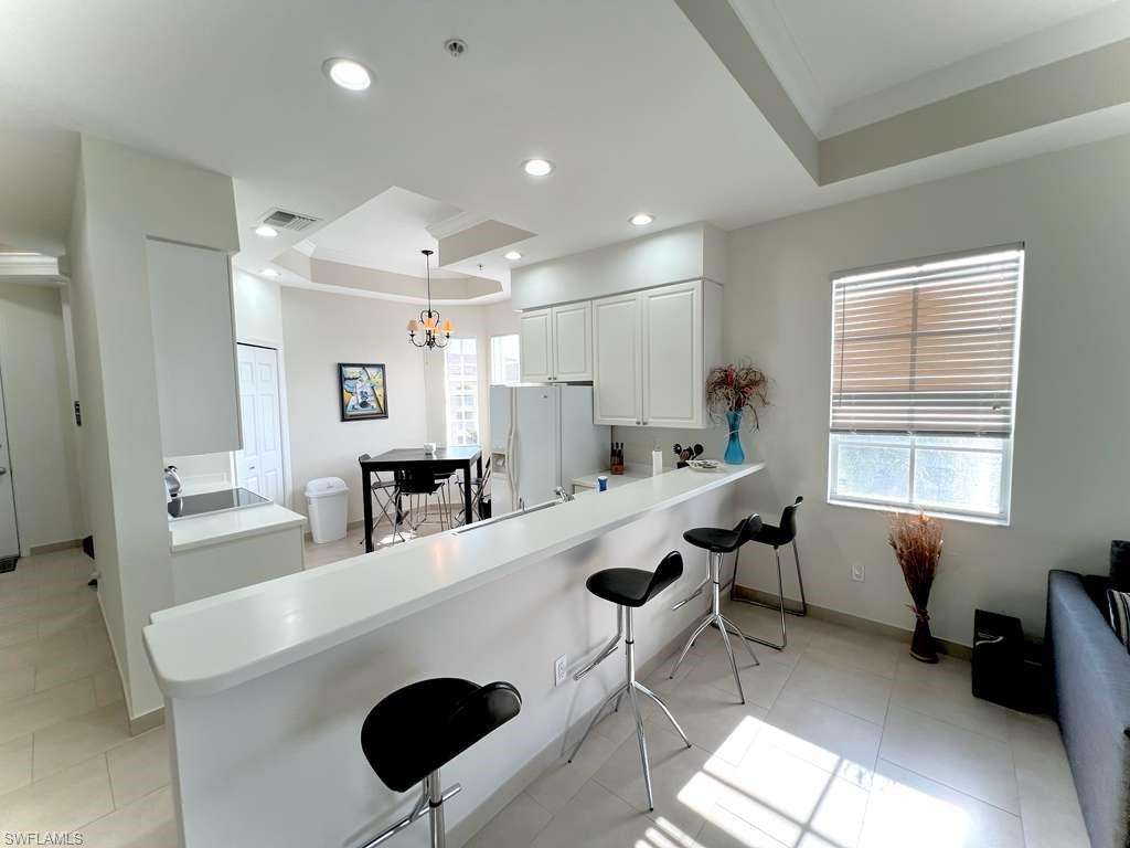 Open-concept kitchen and dining area featuring a breakfast bar, white cabinetry, recessed lighting, and tile flooring