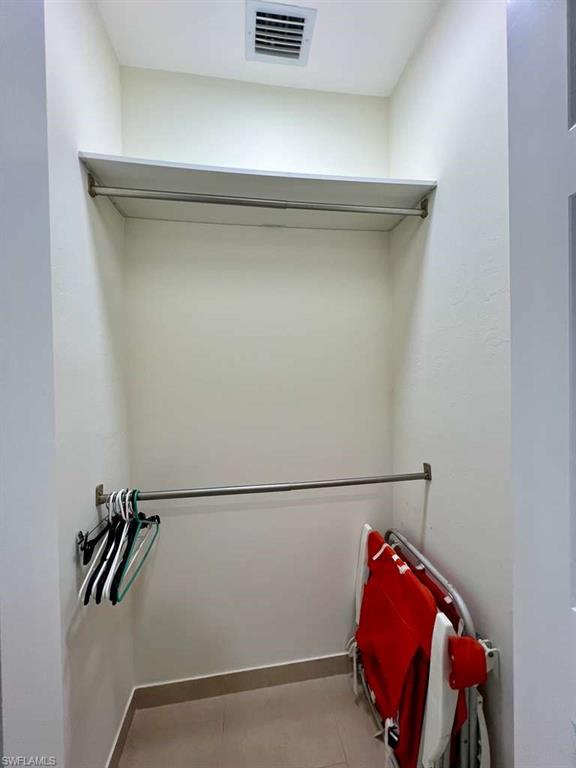 Closet with built-in shelving, dual hanging rods, and tile flooring