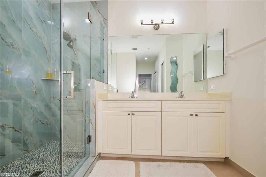 Glass-enclosed shower with blue-toned marbled walls and a mosaic pebble floor