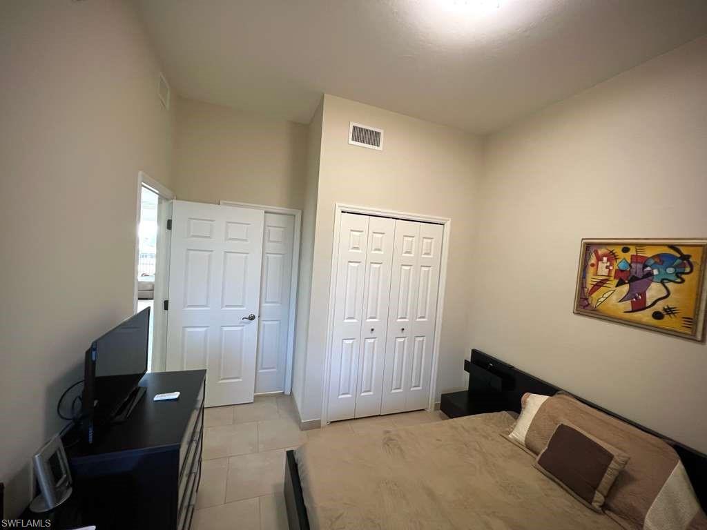 Bedroom featuring neutral wall paint, tiled flooring, two sets of bi-fold doors, and a ceiling-mounted light fixture