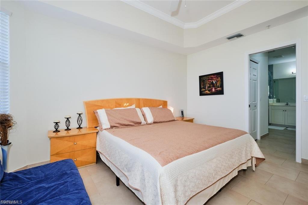 Bedroom featuring a tray ceiling, crown molding, and tiled flooring