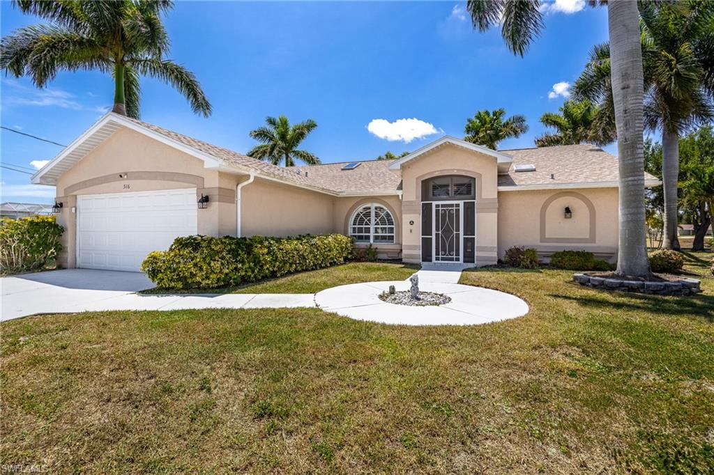 Single-story residence featuring a stucco exterior, an arched entryway, an integrated two-car garage, mature palm trees, and a circular front walkway with a central accent