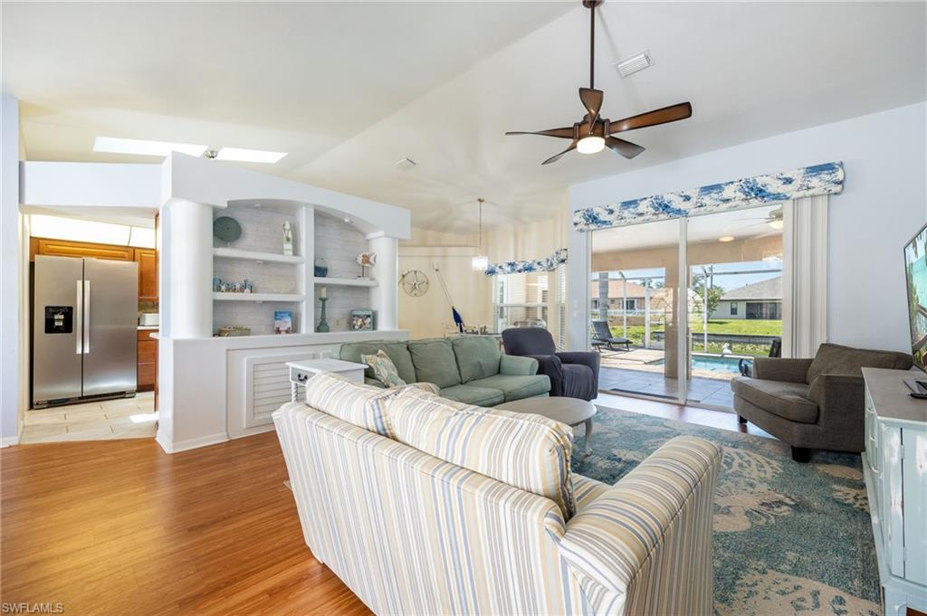 Living area featuring wood-finish flooring, a ceiling fan, and sliding glass doors opening to the screened lanai