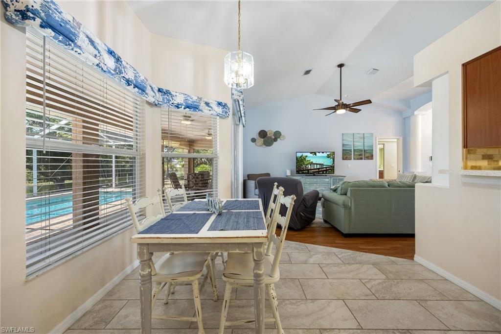 Dining area with large windows, tile flooring, and a contemporary chandelier