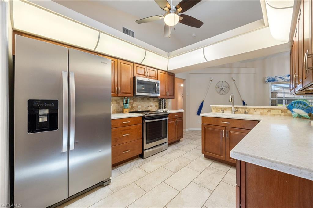 Well-appointed kitchen featuring stainless steel appliances, wood cabinetry, and a textured backsplash