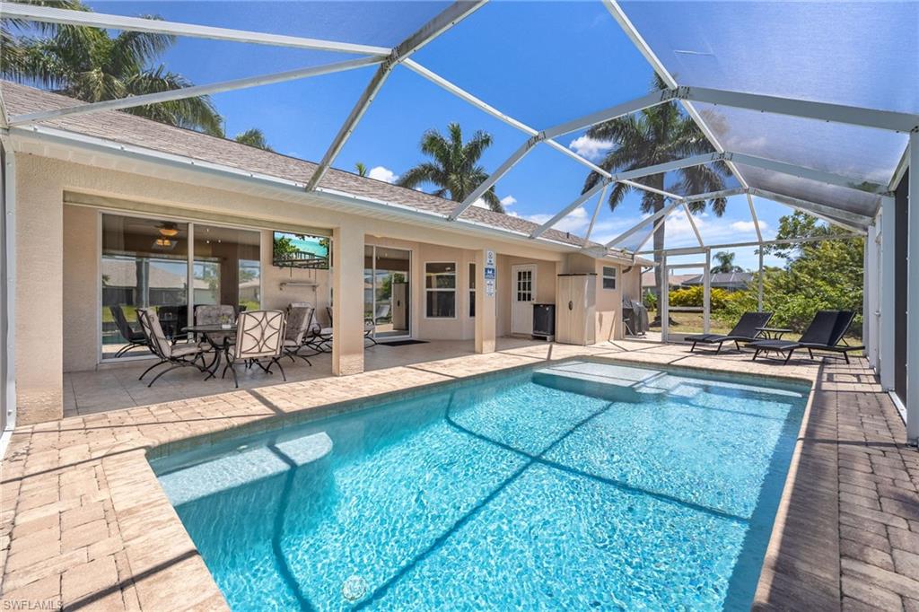 Screened patio featuring a swimming pool with integrated spa, paver deck, and covered outdoor dining area