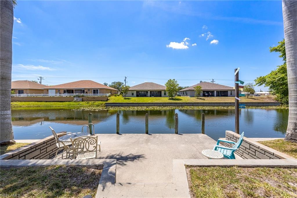 Waterfront property featuring a concrete dock with four pilings, a concrete seawall, and direct canal access