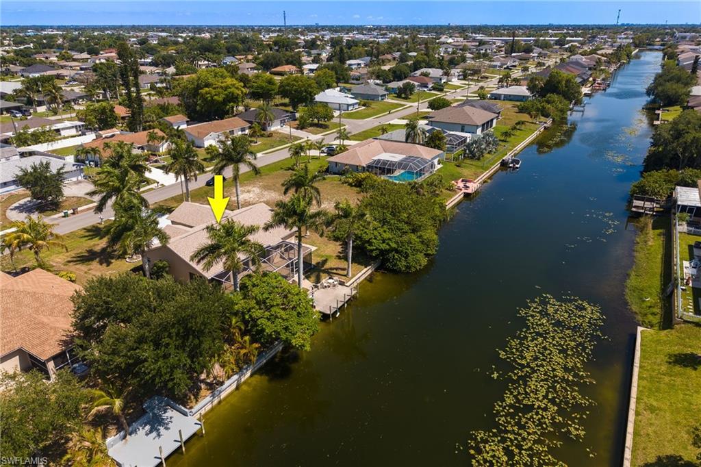 Waterfront property featuring a private dock, screened lanai, mature palm trees, and a canal-front location