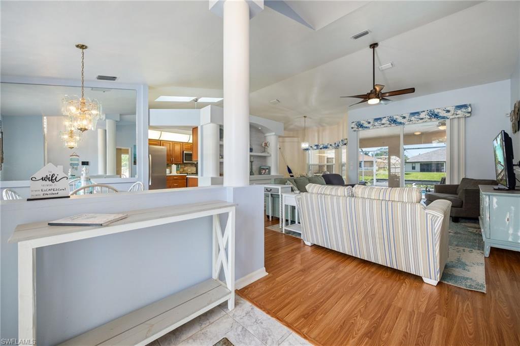 Open-concept living area featuring wood-finish flooring, a ceiling fan with integrated lighting, and a prominent column