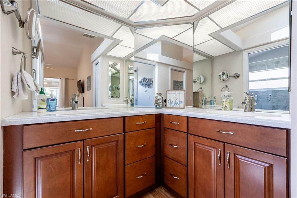 Dual vanity with wood-finish cabinetry, white countertop, and integrated sinks