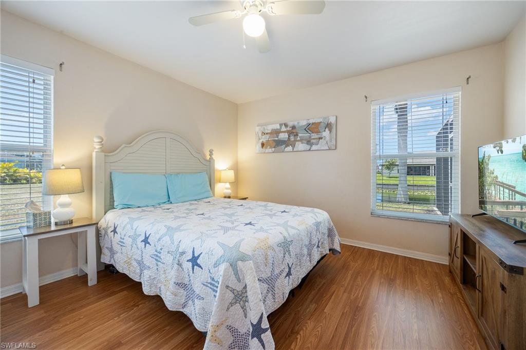 Room featuring wood-finish flooring, two windows with horizontal blinds, and a ceiling fan with integrated lighting
