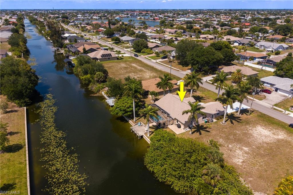 Waterfront property featuring a private boat dock, screened lanai, concrete patio, and a shingled roof