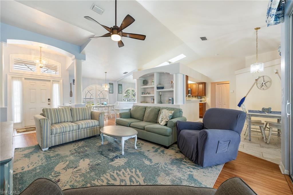 Expansive living area featuring vaulted ceilings, wood-finish flooring, and a ceiling fan
