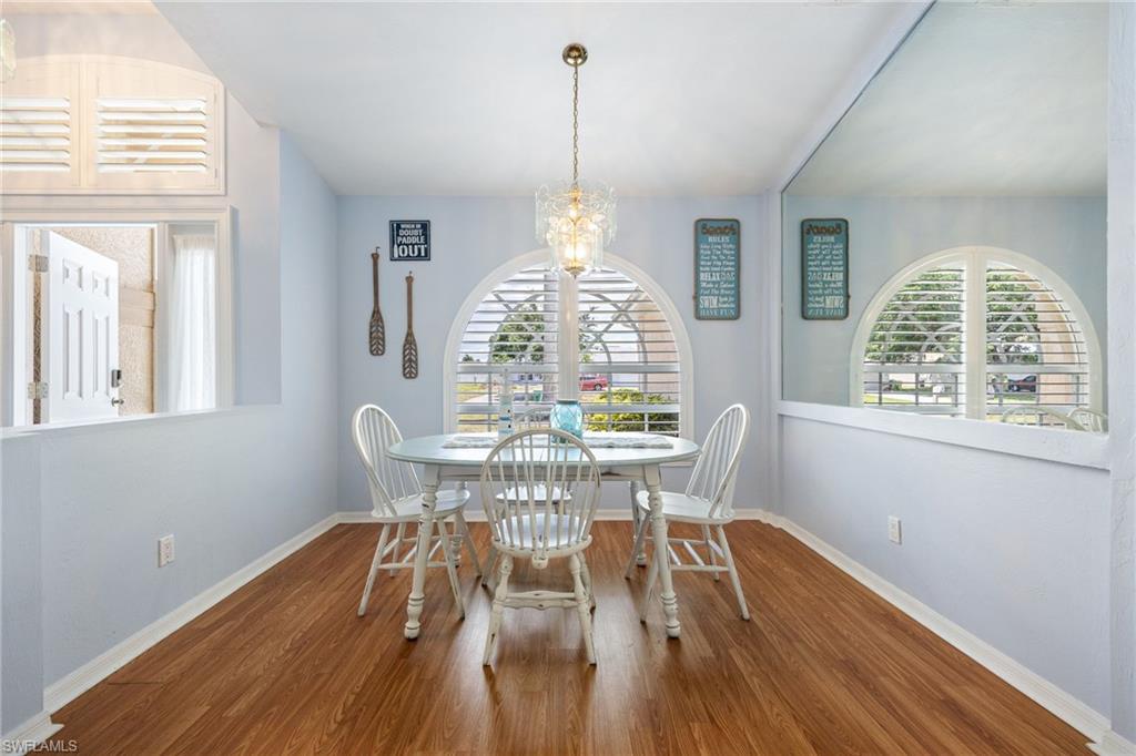Dining space featuring arched windows with plantation shutters, wood-finish flooring, and a decorative ceiling light fixture