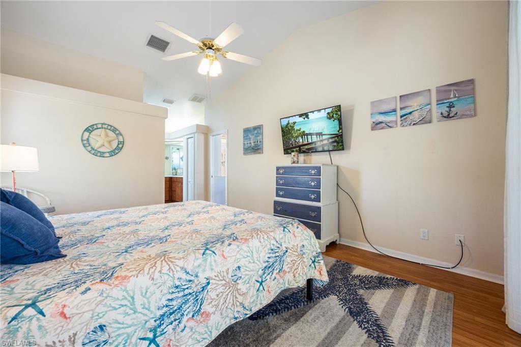 Vaulted ceiling bedroom with light-toned wall finishes and wood-finish flooring