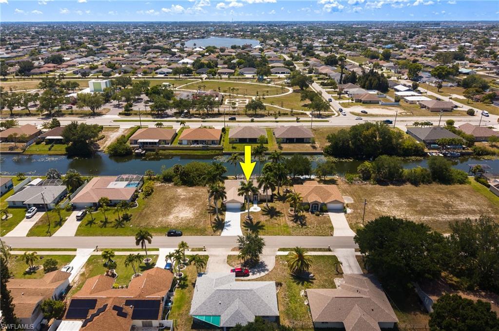 Aerial overview showcasing a residential property with a light-colored roof and an attached garage