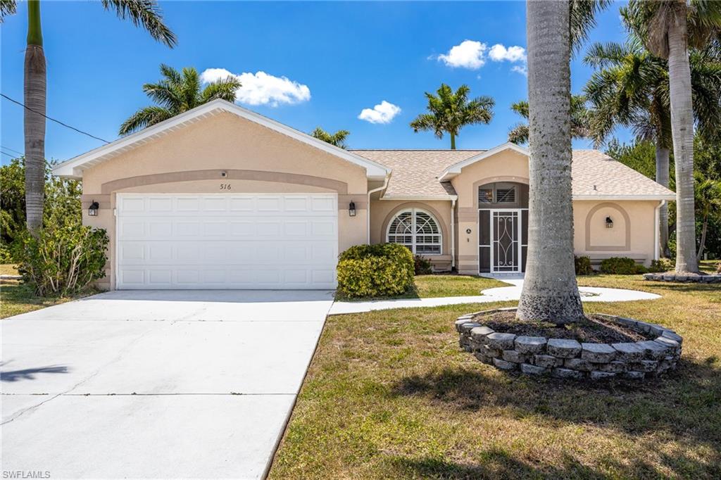Tan stucco exterior featuring a curved entry archway and a white garage door