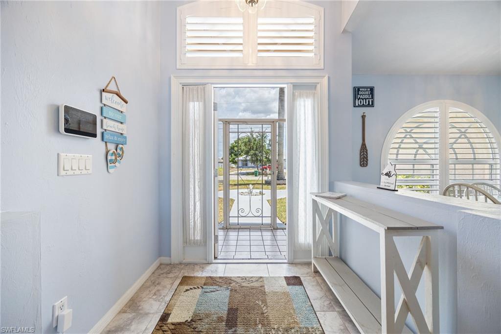 Entryway featuring a decorative wrought-iron security door and transom window with white plantation shutters