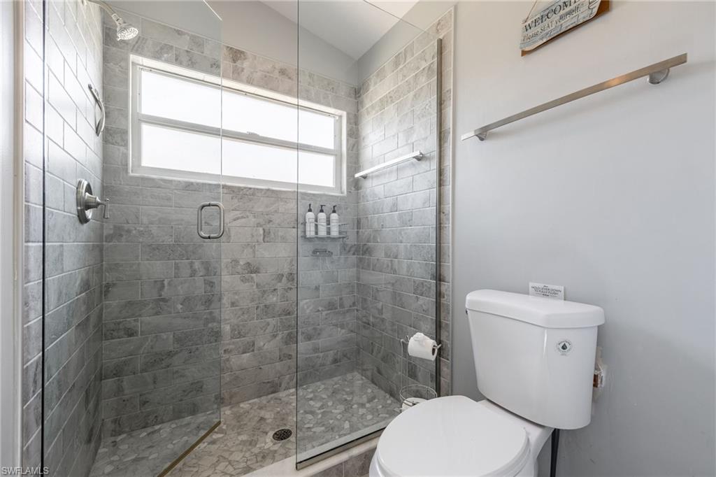 Glass-enclosed shower featuring gray subway tile walls and a pebble-finish floor