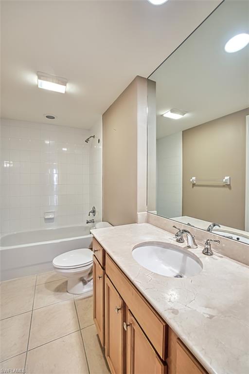 Full bathroom featuring tile patterned floors, vanity, tiled shower / bath combo, and toilet