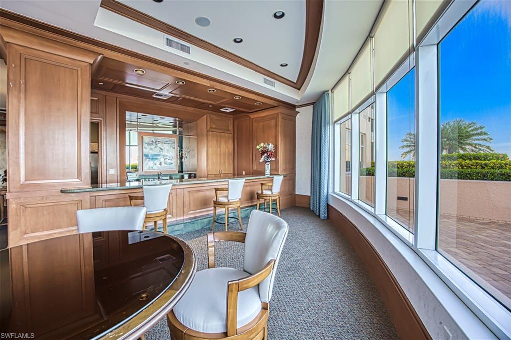 Carpeted dining room featuring a tray ceiling, ornamental molding, and wood walls