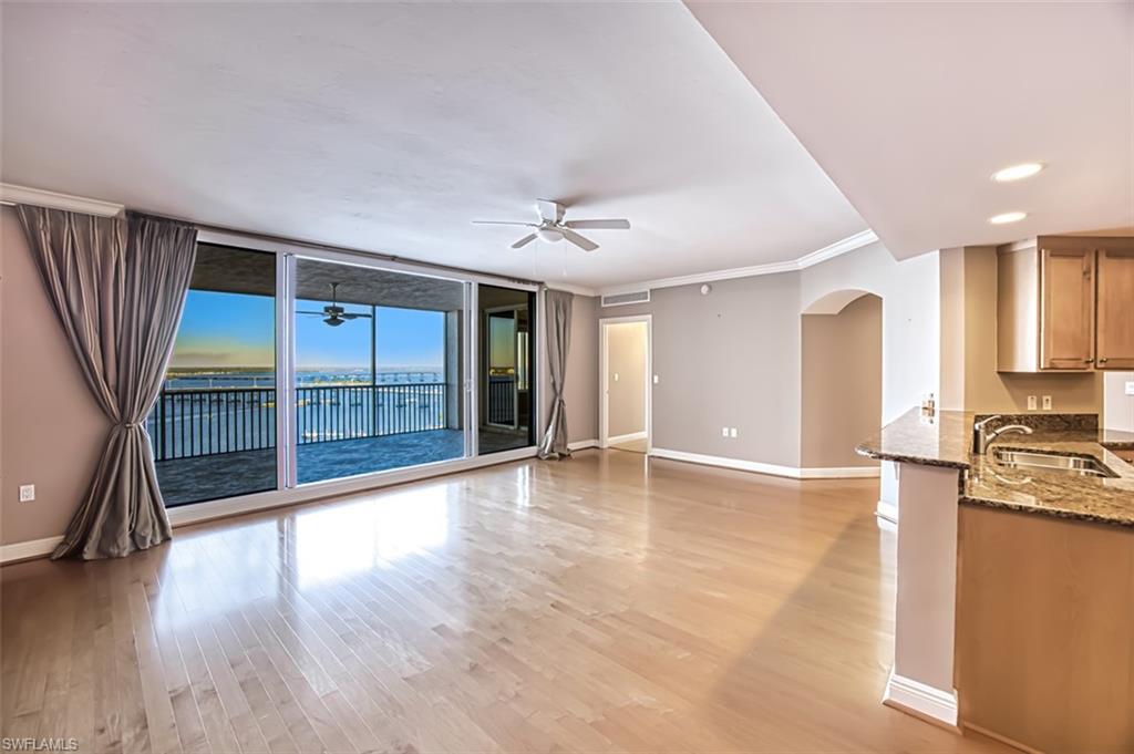 Unfurnished living room with floor to ceiling windows, ceiling fan, sink, light hardwood / wood-style floors, and ornamental molding