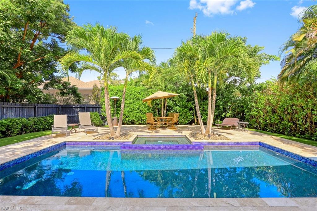 View of pool featuring a patio, fence, and a pool with connected hot tub