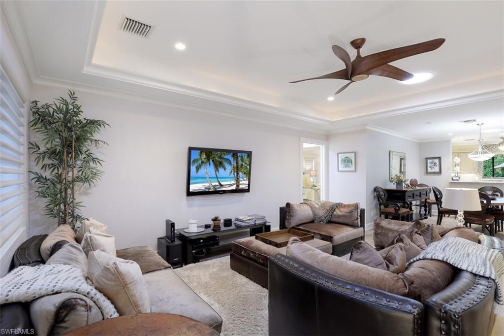 Living area with ceiling fan, a tray ceiling, recessed lighting, and crown molding