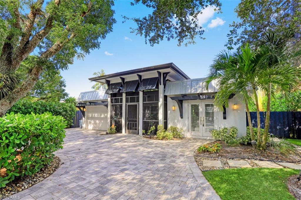 View of front of property featuring french doors, stucco siding, fence, and a garage