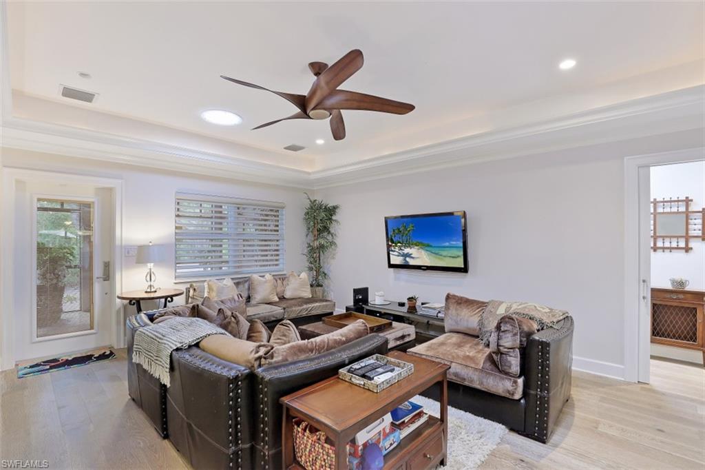 Living area with a tray ceiling, ceiling fan, light wood-type flooring, recessed lighting, and crown molding