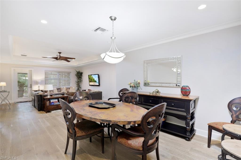 Dining room with crown molding, light wood-style floors, a ceiling fan, recessed lighting, and a tray ceiling