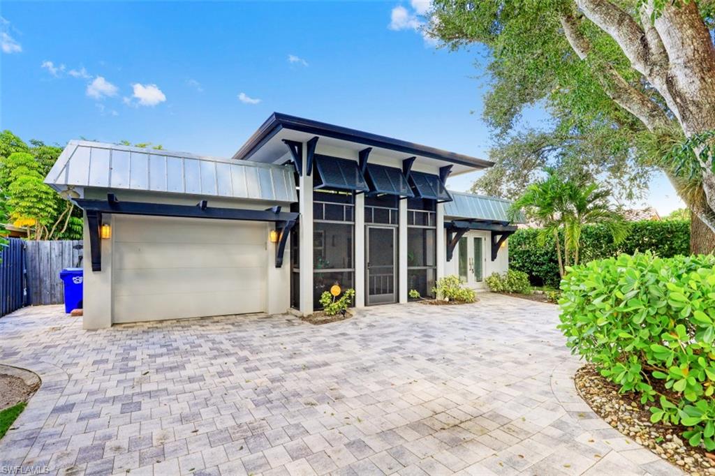 Contemporary home featuring a garage, metal roof, a standing seam roof, and fence