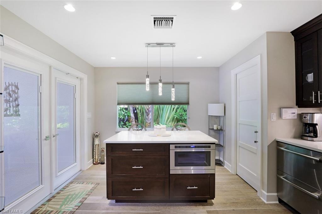 Kitchen with stainless steel appliances, light wood-type flooring, light countertops, dark brown cabinetry, and recessed lighting