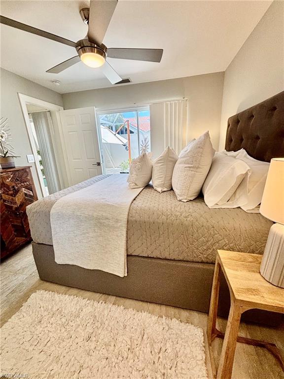 Room featuring wood-finish flooring, a ceiling fan with integrated lighting, and a dark upholstered headboard