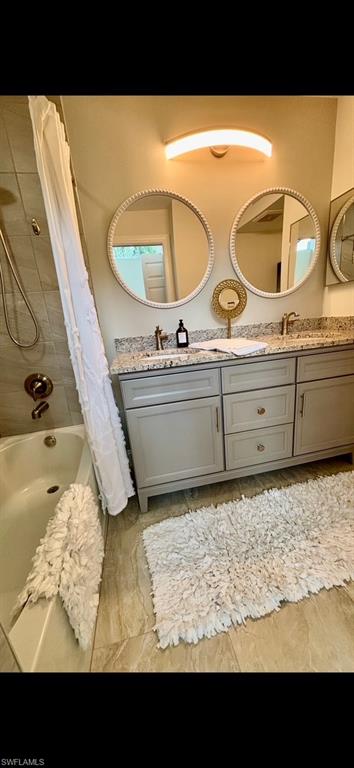 Dual vanity with light gray cabinetry and granite countertops