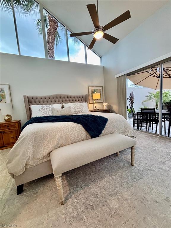 Vaulted ceiling featuring a ceiling fan with integrated lighting, high-level transom windows, and sliding glass doors opening to an outdoor patio