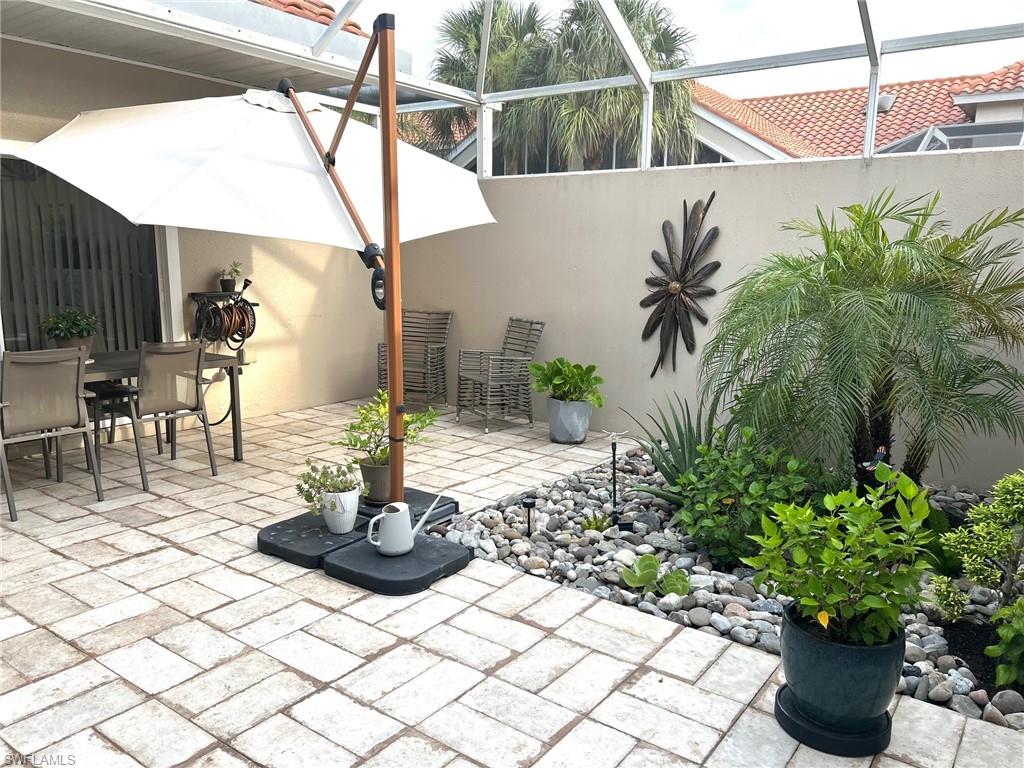 Outdoor patio featuring paver flooring, a robust privacy wall, and an integrated garden bed with varied rockwork and established plantings