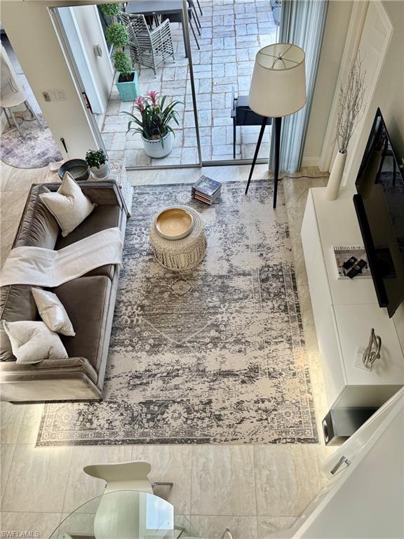 Spacious living area featuring light-toned tile flooring throughout and a full-height glass sliding door