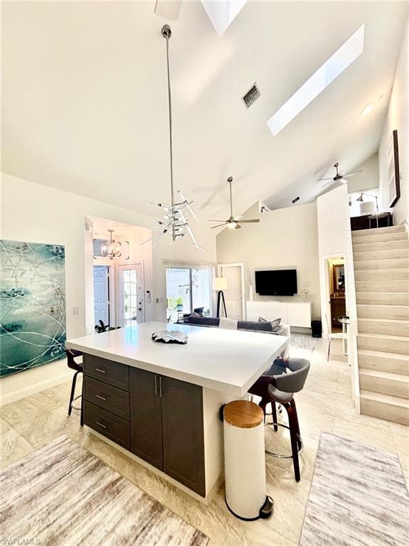 Spacious interior featuring a large kitchen island with ample counter space and storage, vaulted ceilings with skylights, and tile flooring