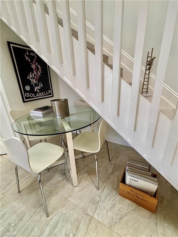 Under-stair alcove featuring light-toned tile flooring and a glass-top table
