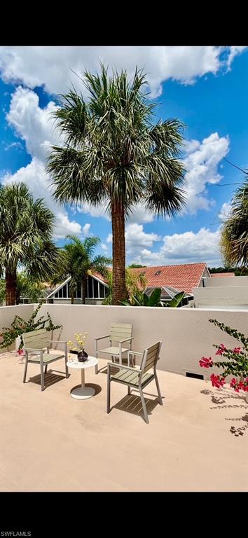 Expansive outdoor terrace featuring a neutral-toned surface, a surrounding privacy wall, and mature palm trees