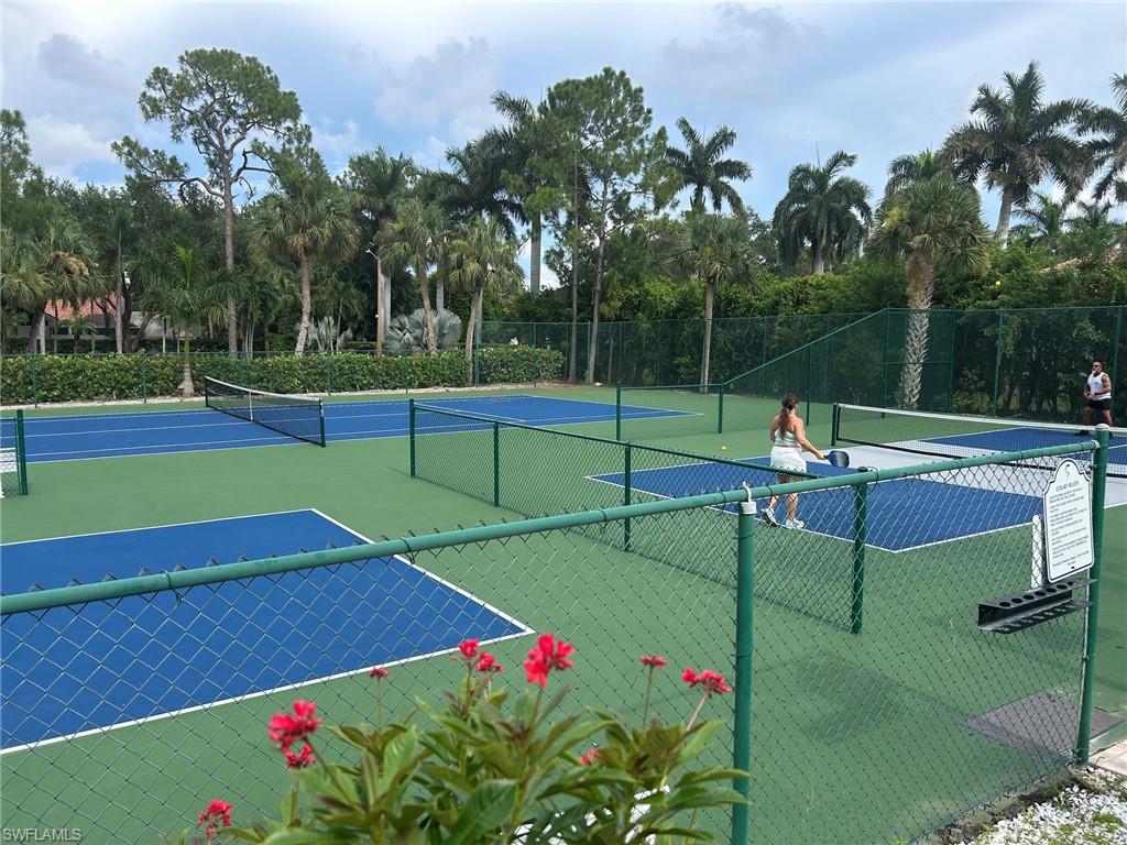 Multiple outdoor pickleball courts and tennis featuring green and blue surfacing, surrounded by lush mature landscaping and fencing