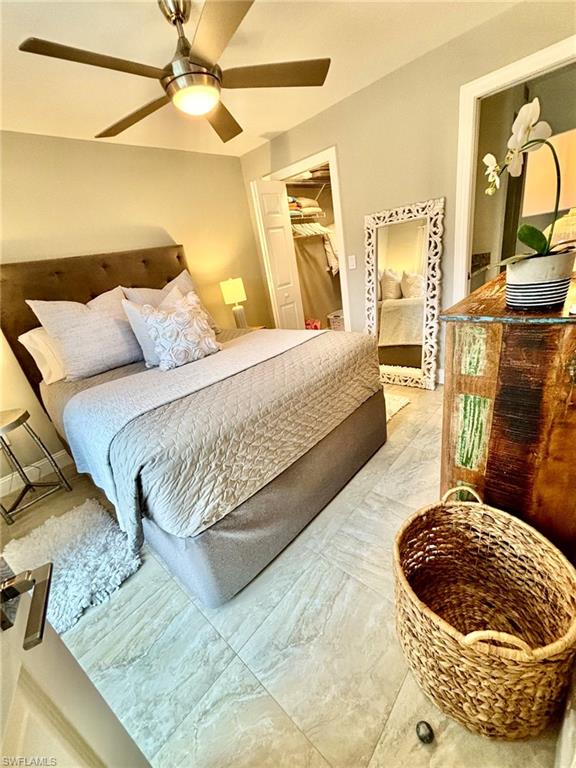 Neutral-toned bedroom featuring large format tile flooring, a ceiling fan with integrated lighting, and a closet with bifold doors
