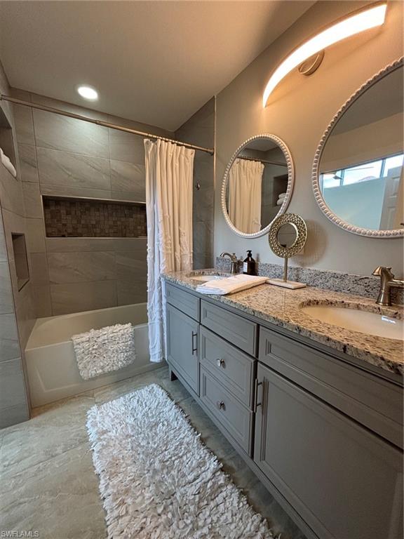 Bathroom featuring a dual vanity with a speckled countertop, undermount sinks, and grey cabinetry