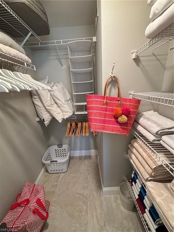 Walk-in closet featuring light beige wall paint and light-toned tile flooring