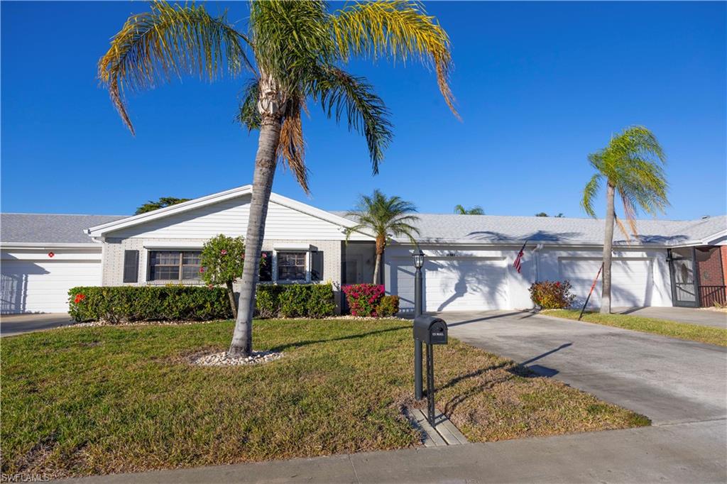 Single story home featuring an attached garage, driveway, a front yard, and brick siding